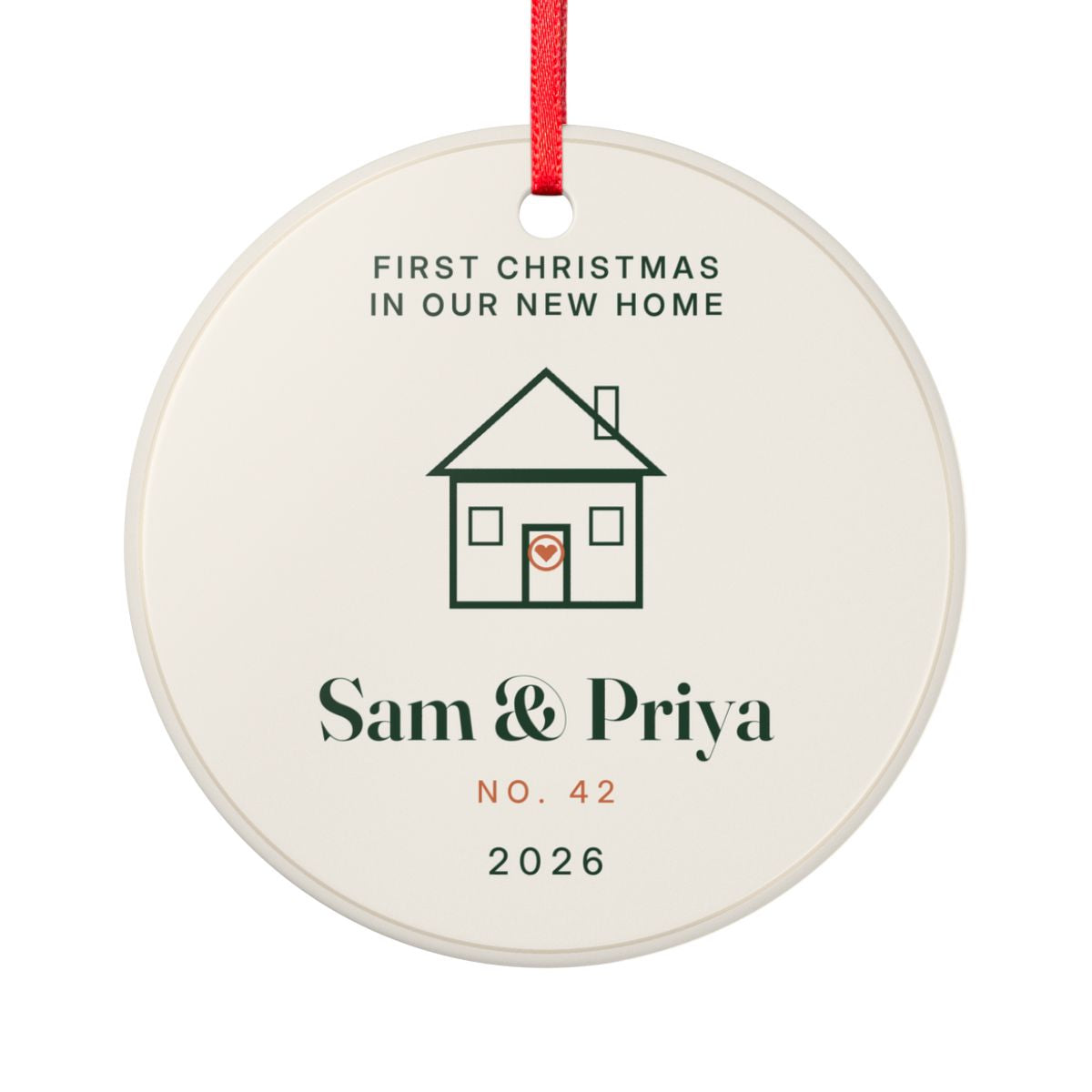 Round First Christmas in Our New Home ceramic ornament on a red ribbon with a line-drawn house, the names Sam and Priya, No. 42 and the year 2026