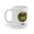 Pet photo mug mock-up with a round sample spaniel photo on a lawn, 'Milo' and 'World's best boy', handle on the left