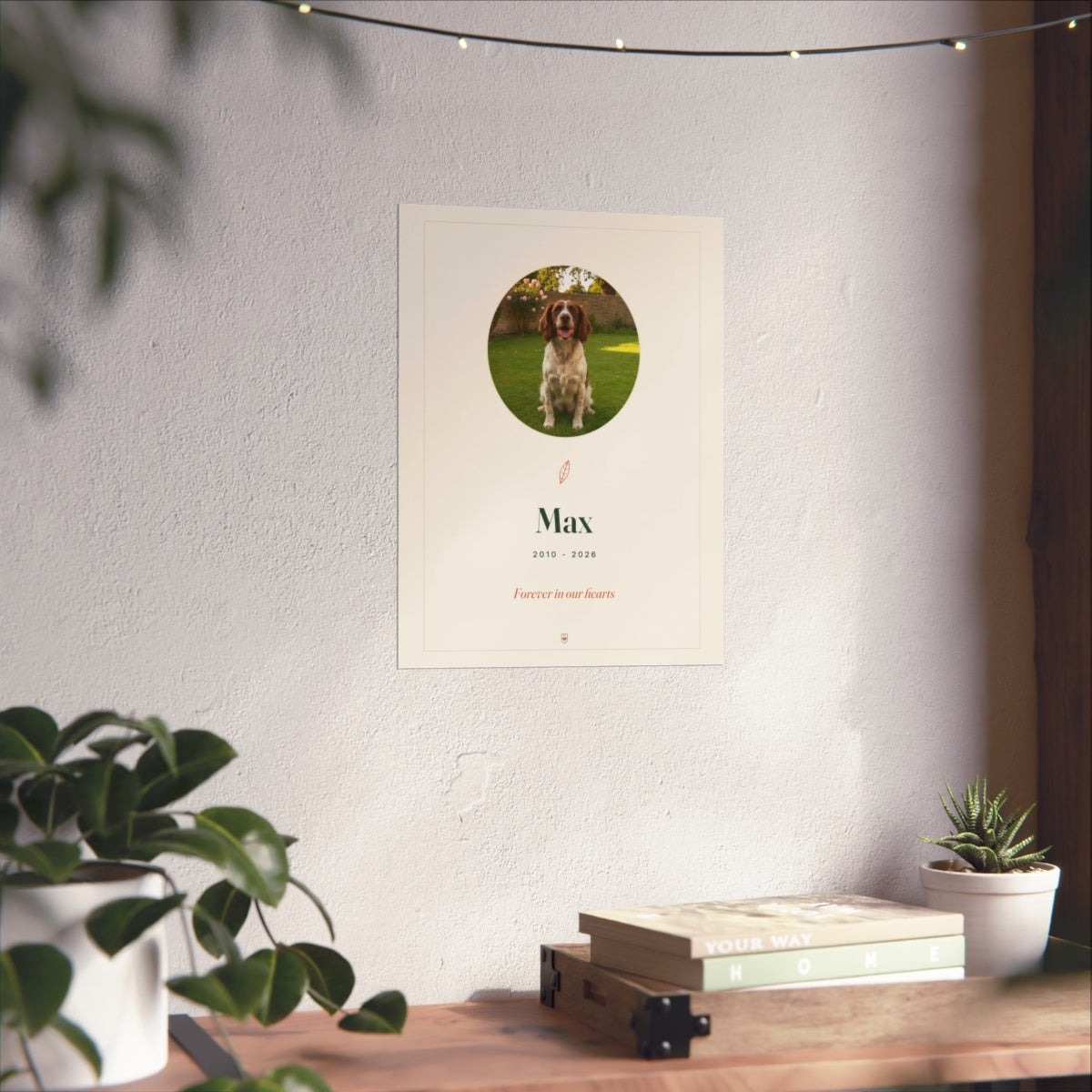 Pet memorial print mock-up on a white wall above a wooden desk with books and a small potted plant