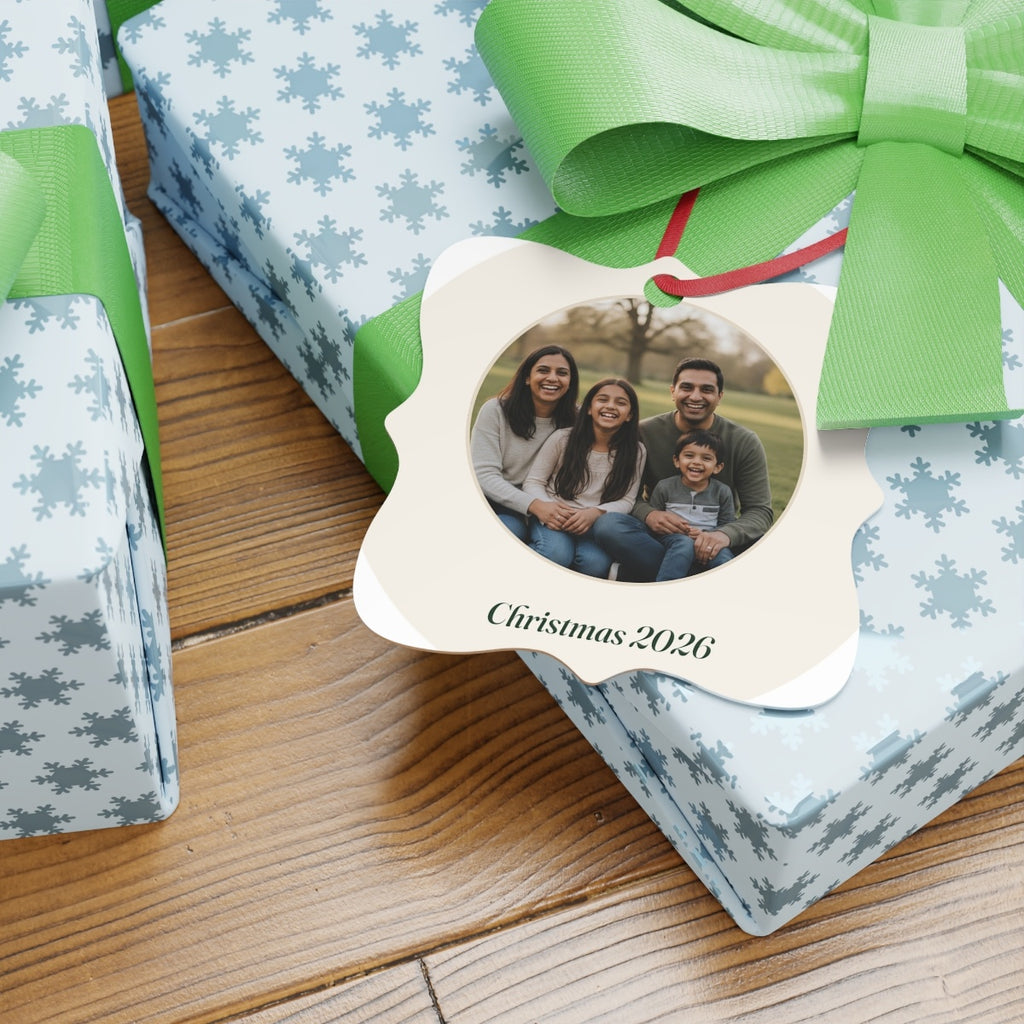 Photo aluminium ornament mock-up resting on snowflake-wrapped gifts with green bows, 'Christmas 2026' beneath the photo