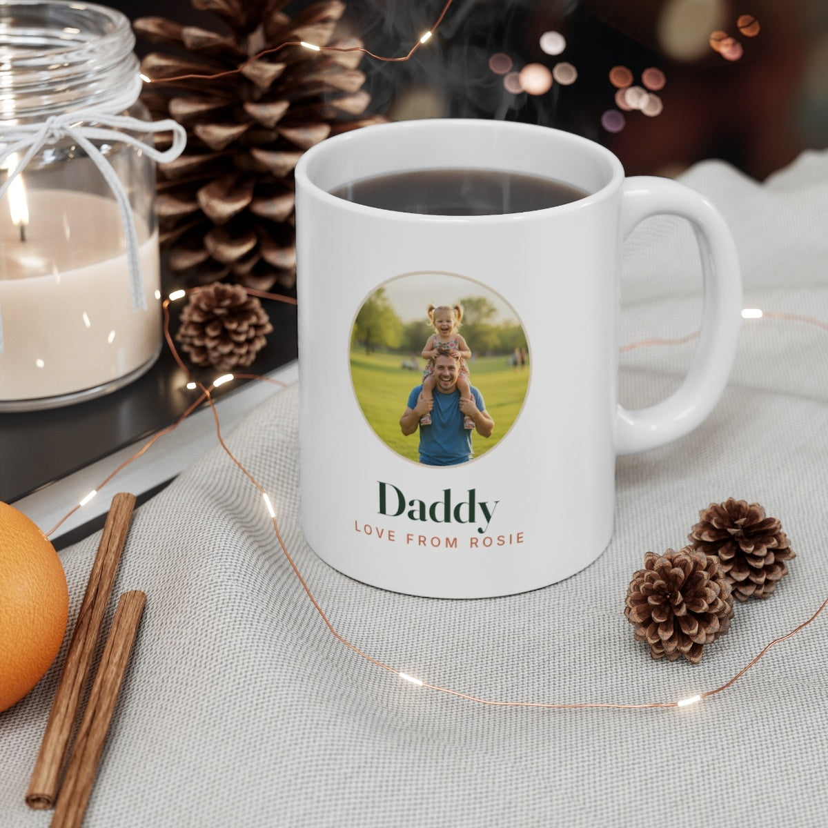 Personalised Daddy photo mug mock-up filled with coffee on a table with pine cones, a candle and fairy lights