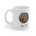 Personalised new home photo mug mock-up with a red-brick house in a round photo, 'No. 42' and 'Home since March 2026'