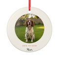 Pet memorial photo ceramic Christmas ornament mock-up with a sample spaniel photo, '2010 to 2026' and 'Max', on a red ribbon