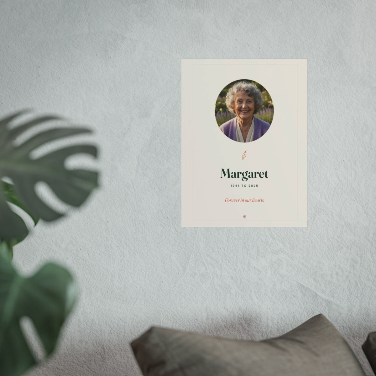 In Loving Memory photo print mock-up hung on a pale wall beside a monstera plant and a grey sofa, shown at the larger size