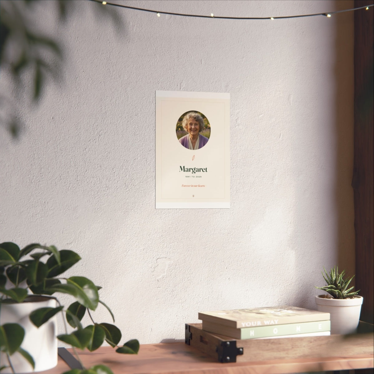 In Loving Memory photo print mock-up at the smaller size on a white wall above a desk with books and plants