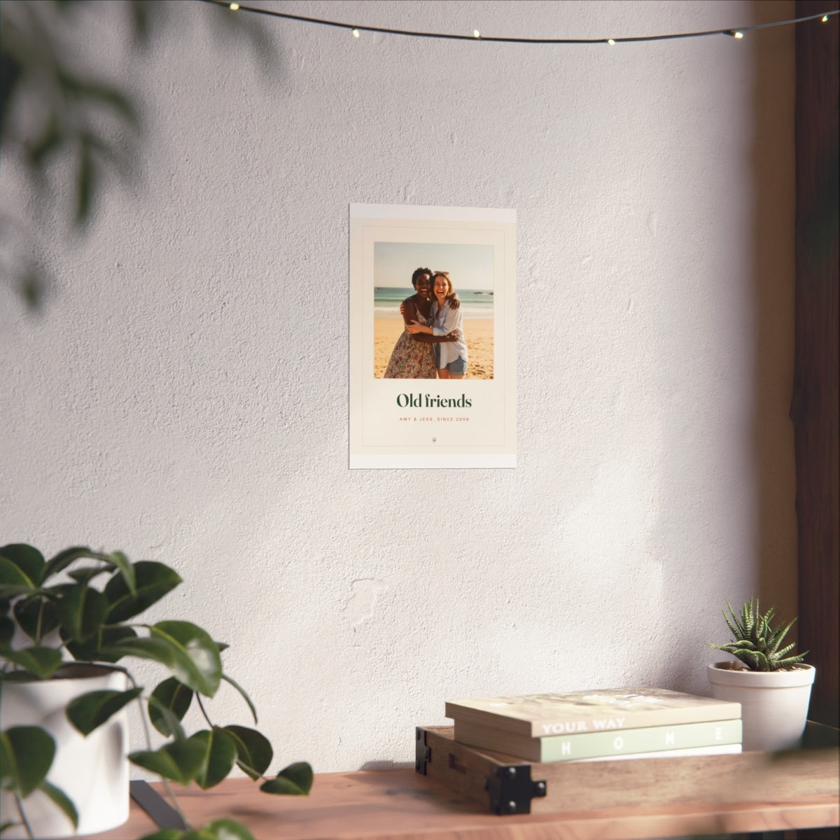 Photo print for friends mock-up in the smaller size on the sunlit white wall above the shelf, fairy lights overhead