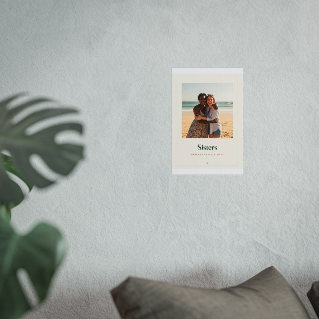 Sisters photo print mock-up at the smaller size on a pale wall beside a monstera plant and a grey sofa