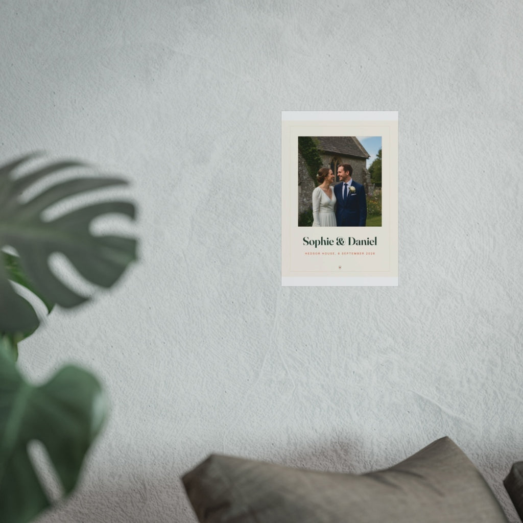 Wedding photo print mock-up shown smaller on the pale wall above the grey sofa, monstera leaf in front