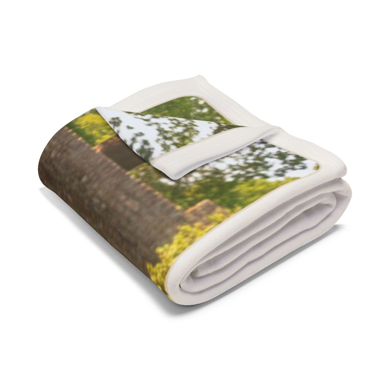 Dog photo fleece blanket folded into a bundle, showing the white border and part of the garden photo
