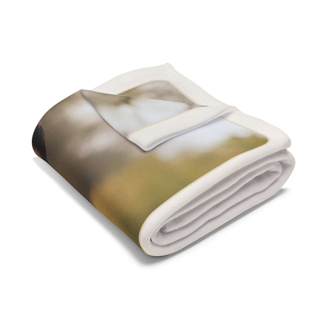 Family photo fleece blanket folded into a bundle, showing the white border and a blurred part of the park photo