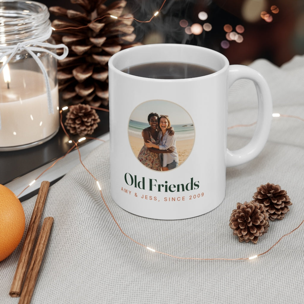 Photo mug for friends mock-up filled with coffee on a table with a candle, pine cones, cinnamon sticks and fairy lights