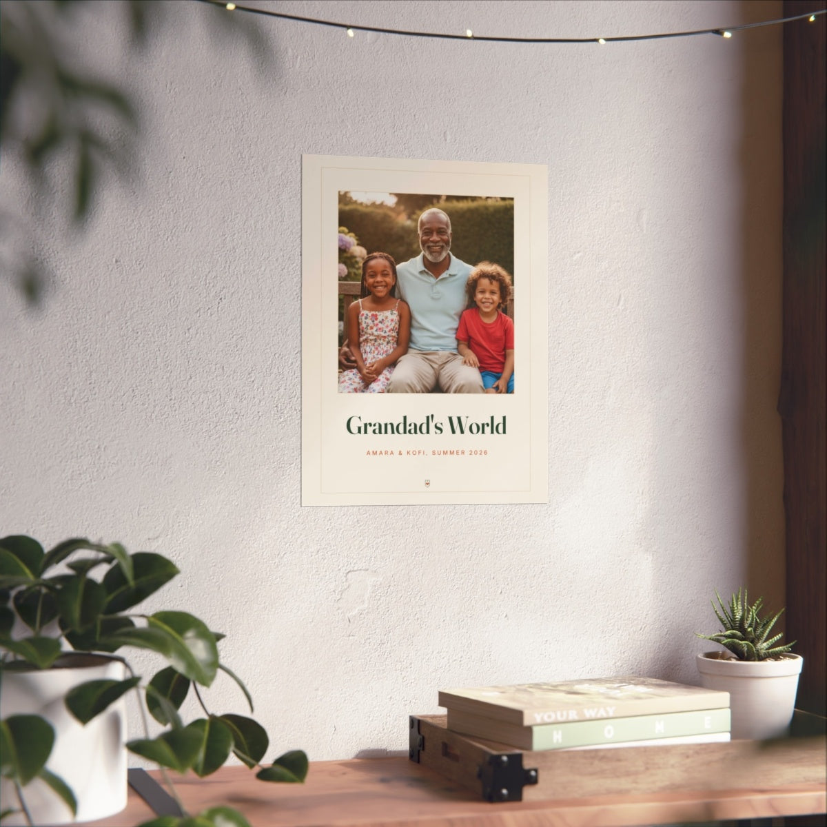 Grandparents photo print mock-up on a white wall above a wooden desk with books, plants and a string of fairy lights