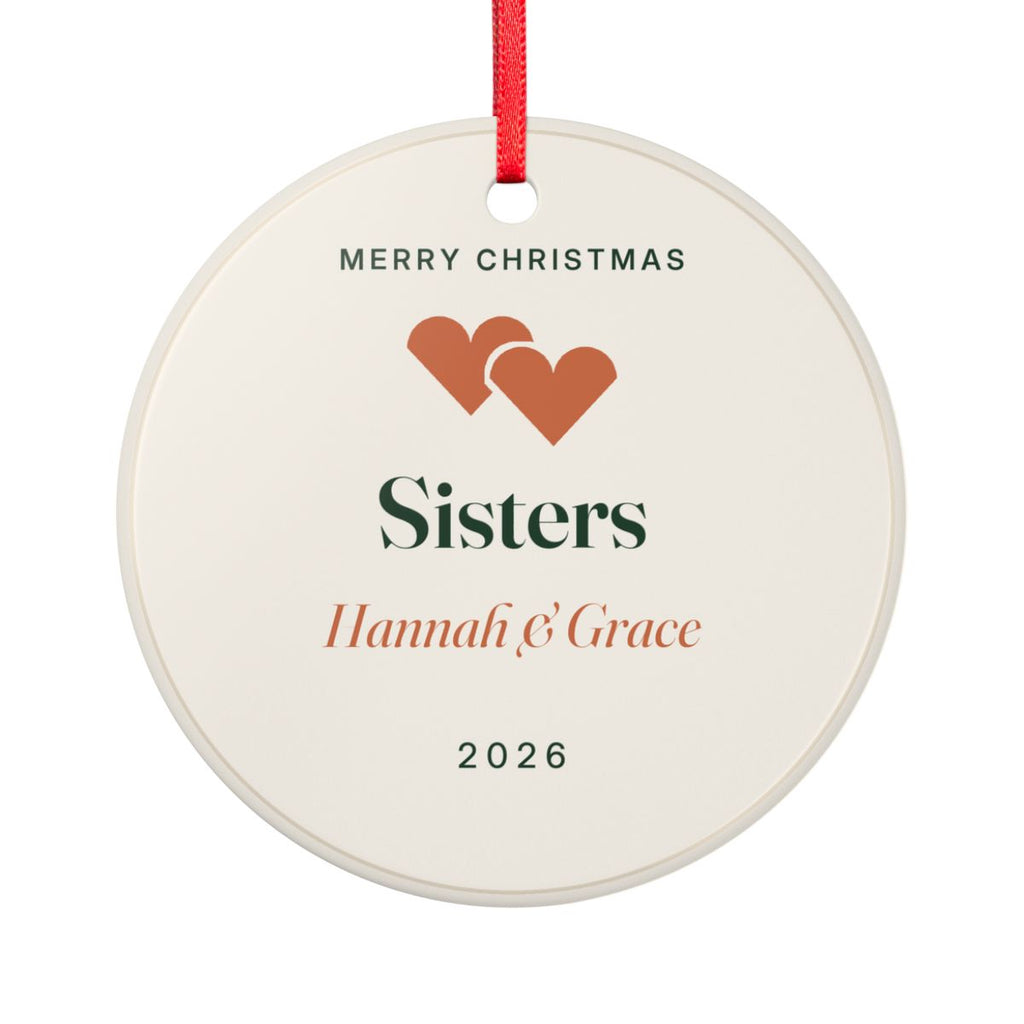 Sisters ceramic Christmas ornament mock-up seen from the other side, with the same two orange hearts, 'Sisters', 'Hannah & Grace' and '2026'