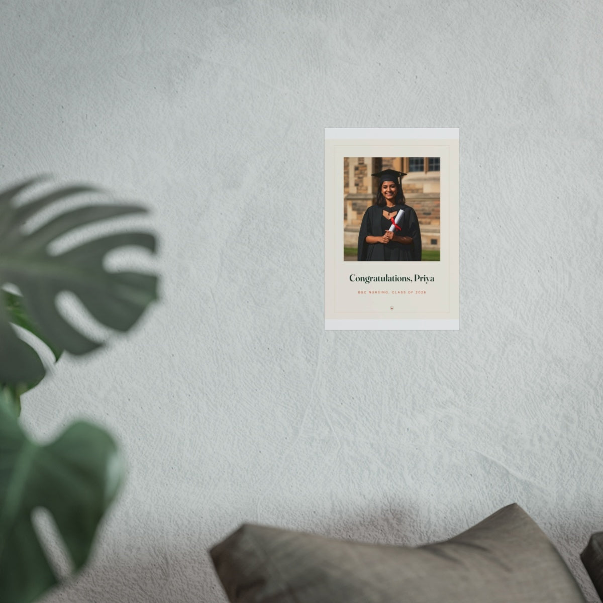 Personalised graduation photo print mock-up at the smaller size on a pale wall above a sofa beside a monstera plant