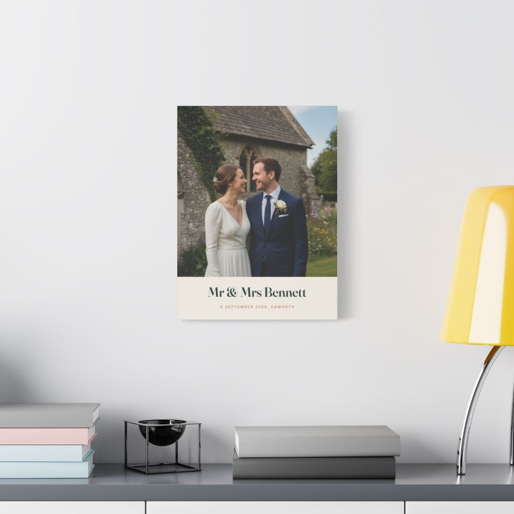 Personalised wedding photo canvas mock-up on a white wall above a desk with books and a yellow lamp