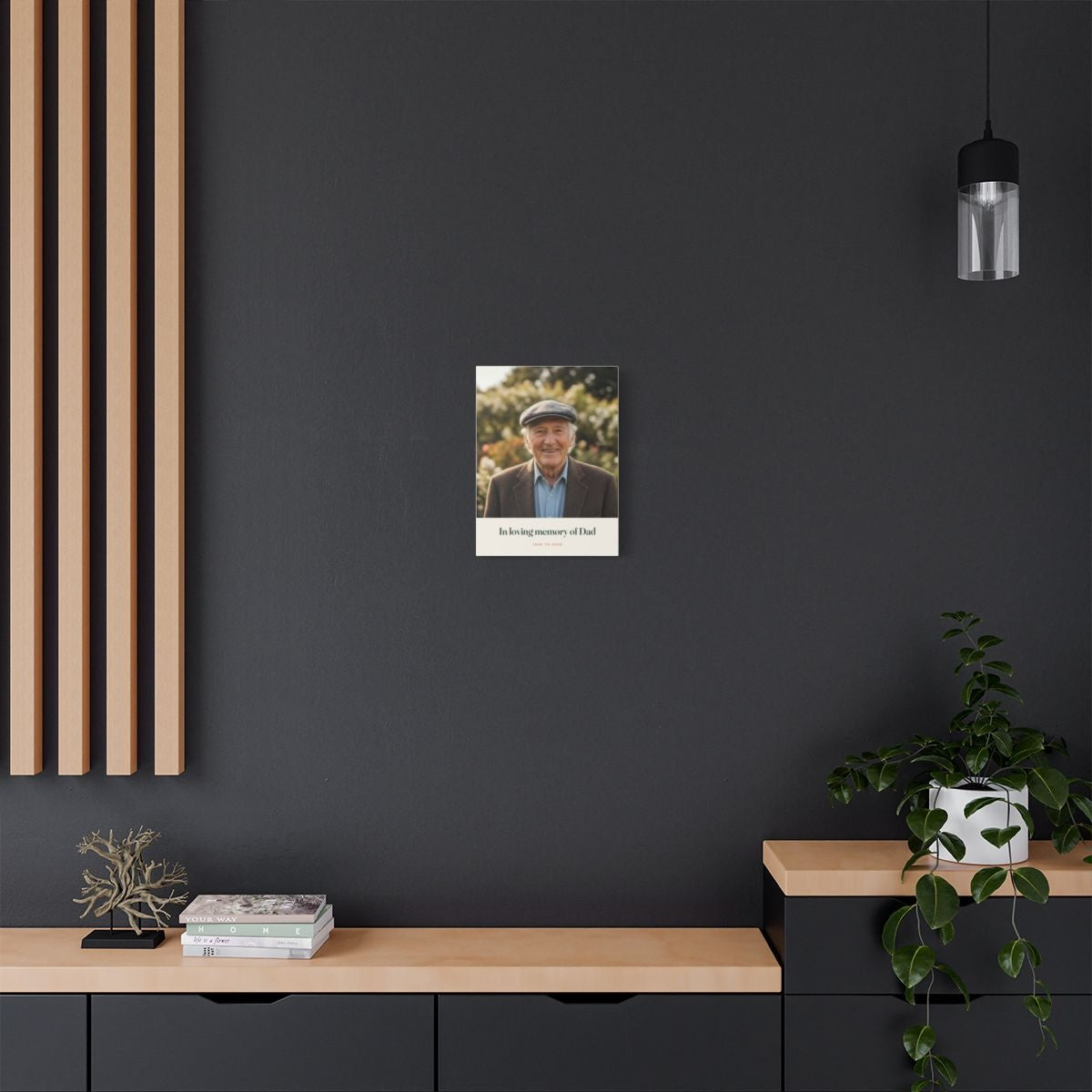 Personalised in loving memory photo canvas mock-up on a dark grey wall above a sideboard with books and a trailing plant