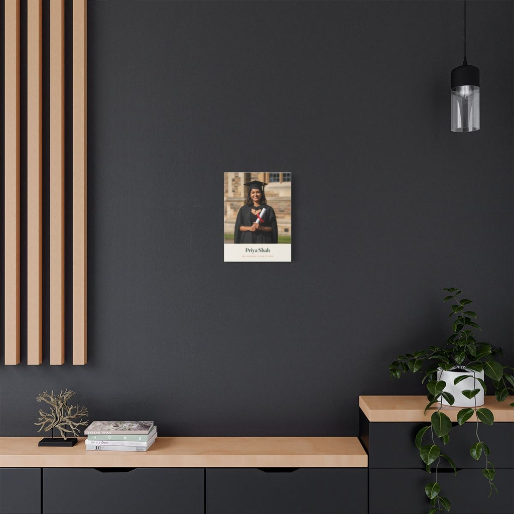 Personalised graduation photo canvas mock-up on a dark grey wall with wooden slats, above a sideboard with trailing plants