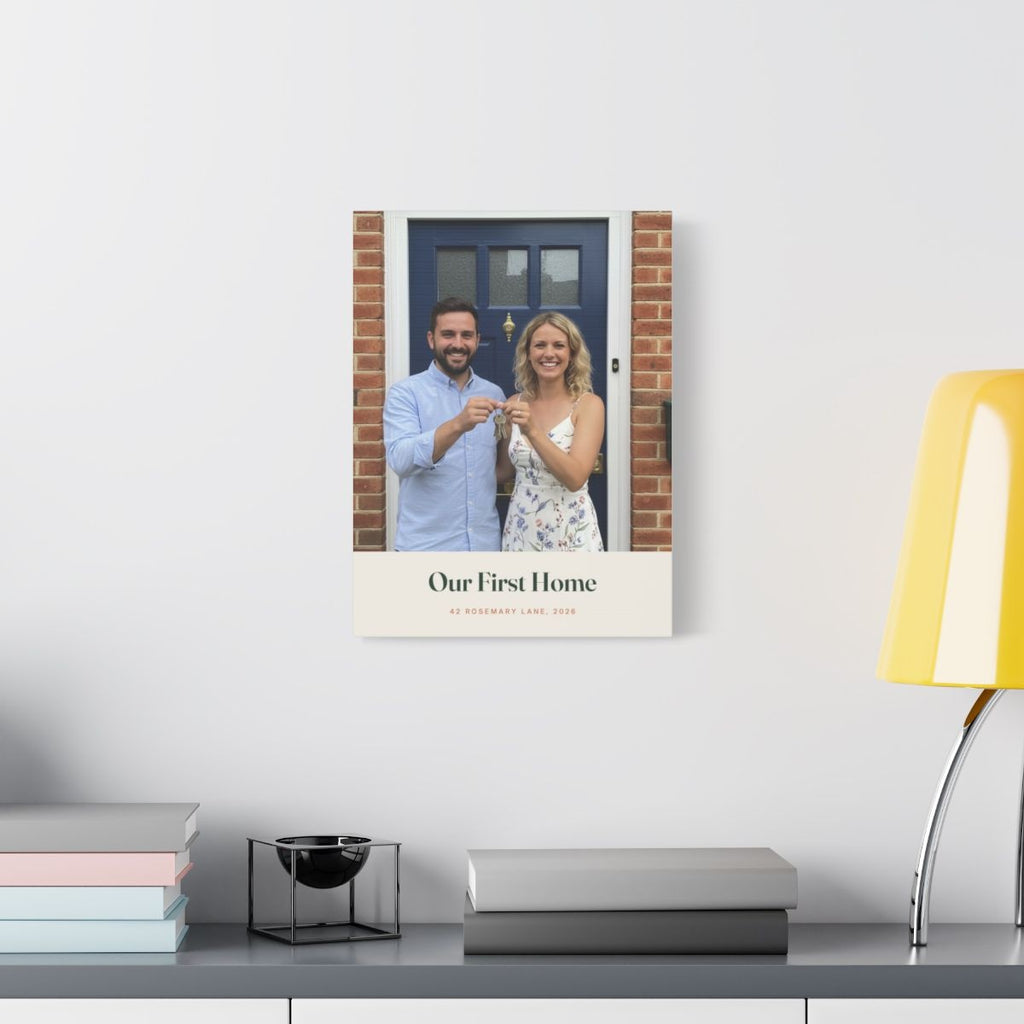 Personalised new home photo canvas mock-up hung on a pale wall above a desk with books and a yellow lamp