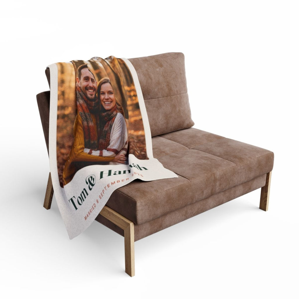 Personalised couple photo fleece blanket mock-up draped over a brown armchair with the couple's photo and names showing