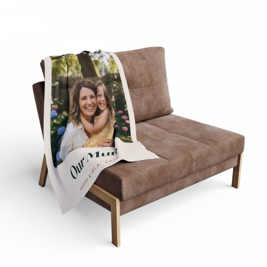 Personalised Mum photo fleece blanket mock-up draped over the back of a brown sofa with the 'Our Mum' caption showing