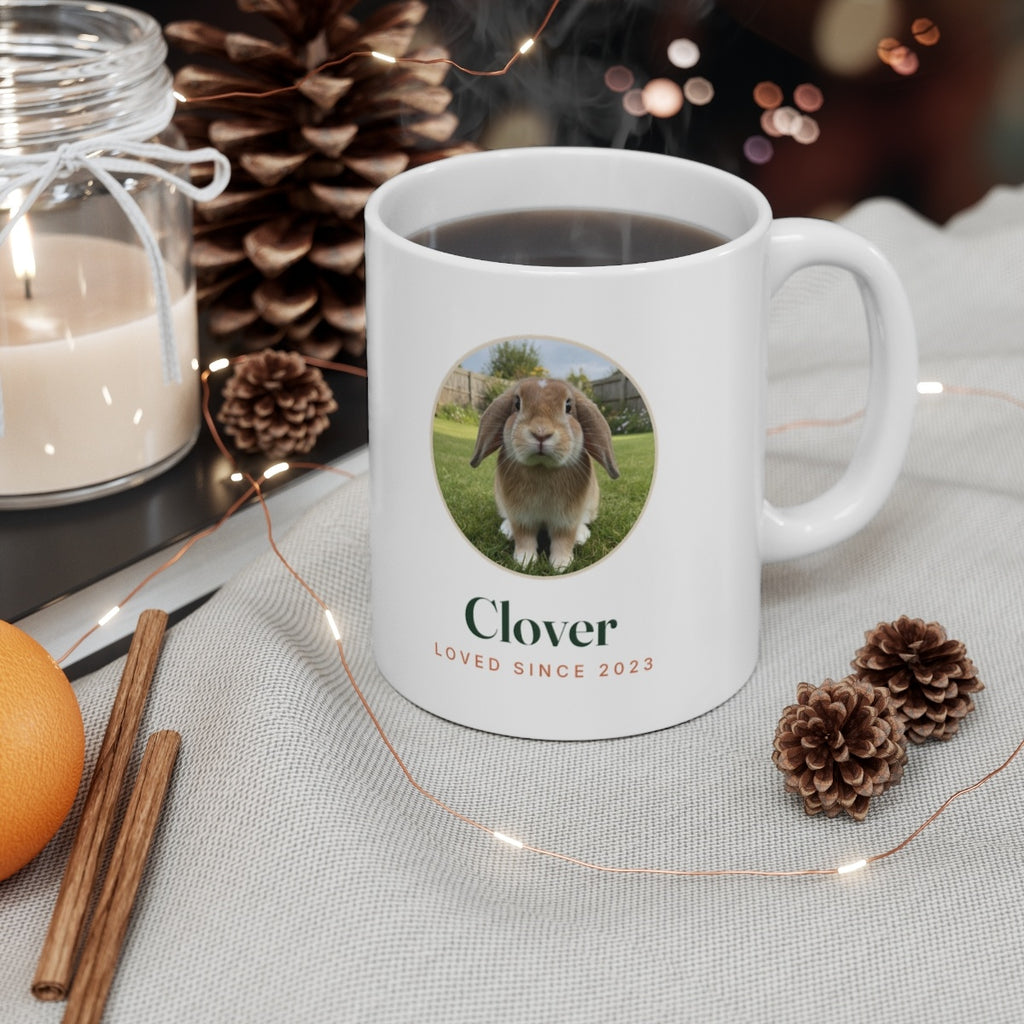 Rabbit photo mug mock-up filled with coffee on a table with a candle, pine cones and fairy lights