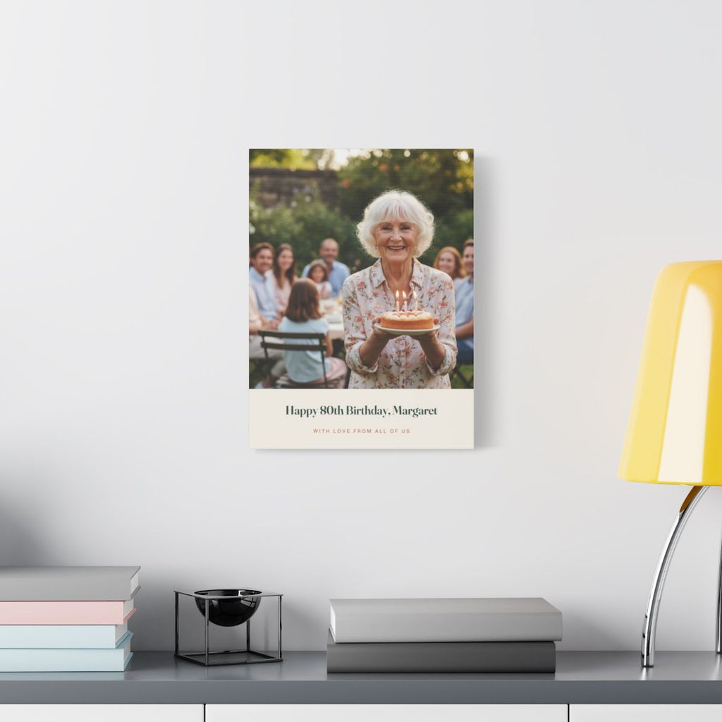 Birthday photo canvas on a pale wall above a desk with a yellow lamp and a stack of books