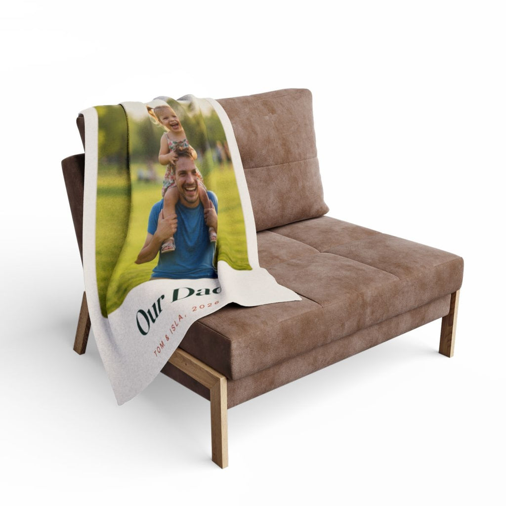 Personalised Dad photo fleece blanket mock-up draped over a brown armchair with the park photo and 'Our Dad' showing