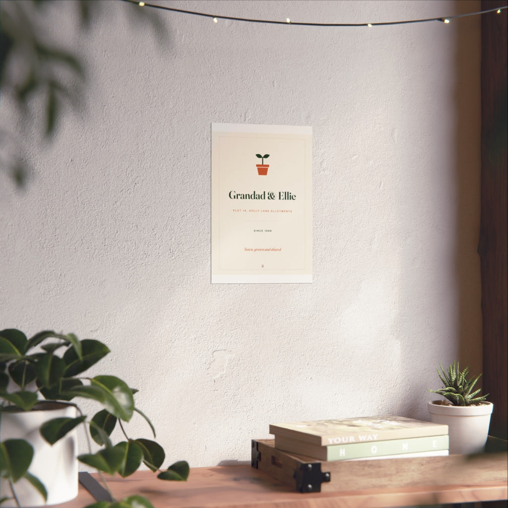Allotment print mock-up at the smaller size on a white wall above a desk with books and plants