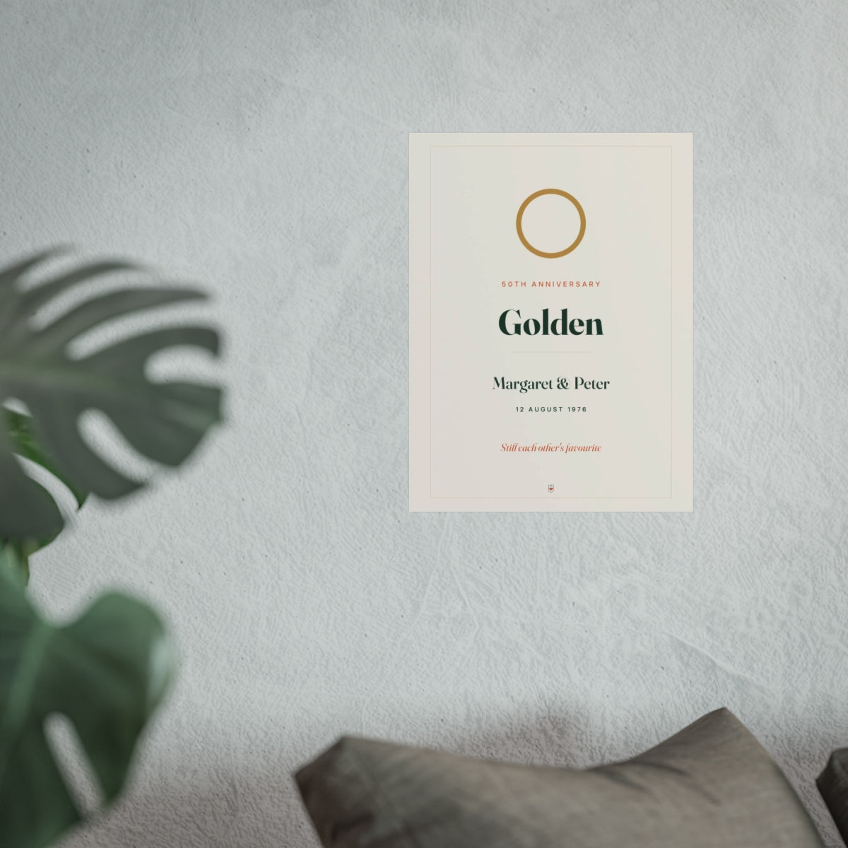 Anniversary print mock-up hung on a pale wall beside a monstera plant and a grey sofa, shown at the larger size
