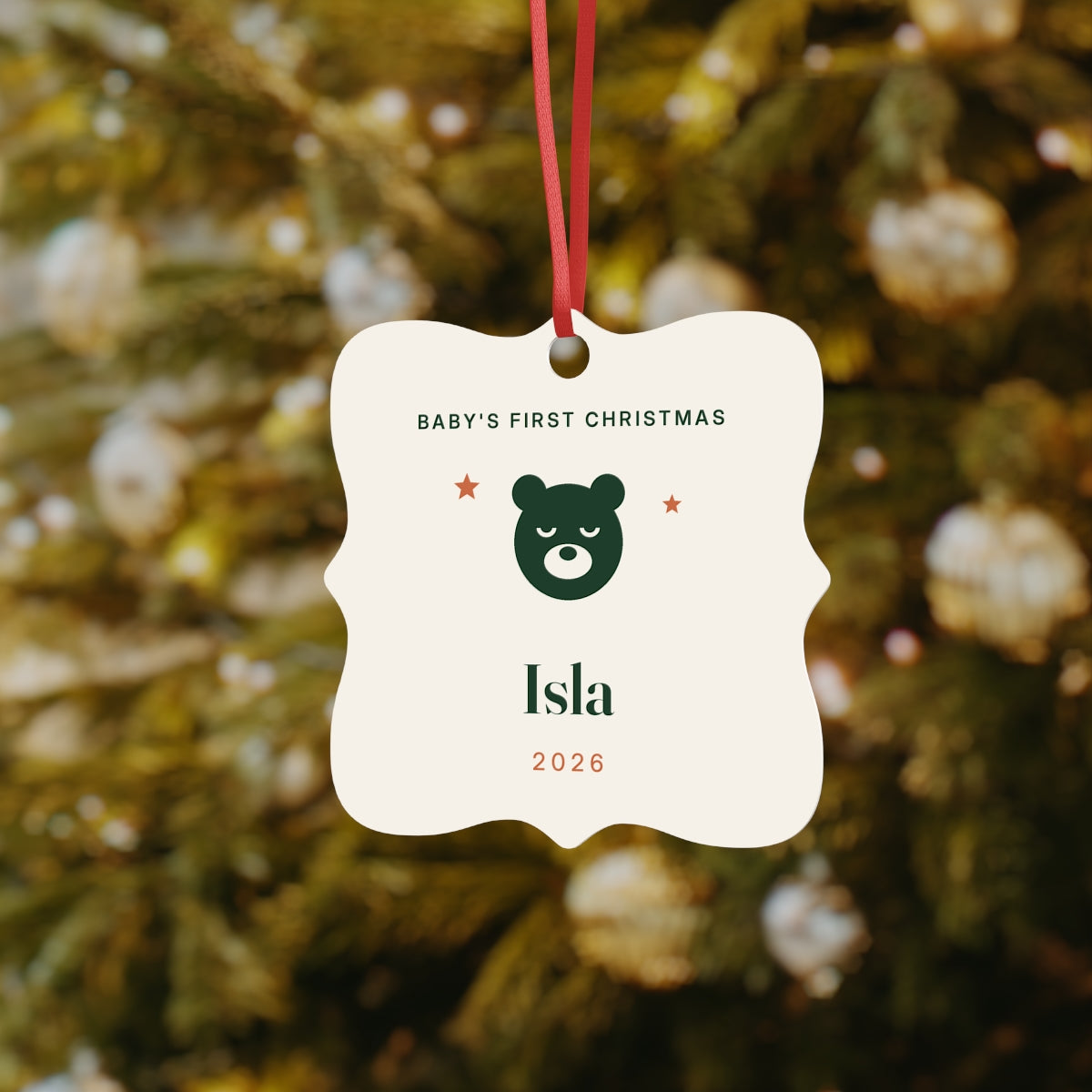 Baby's First Christmas aluminium ornament mock-up hanging on a Christmas tree, bear face and sample name 'Isla'