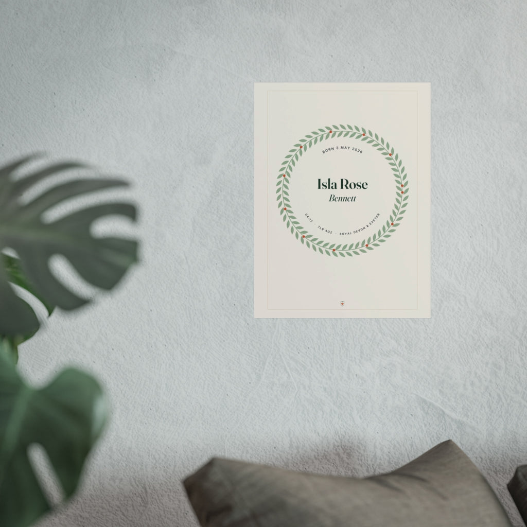 Birth details print mock-up on a white wall beside a monstera plant and a grey sofa cushion, 'Isla Rose Bennett' in a wreath