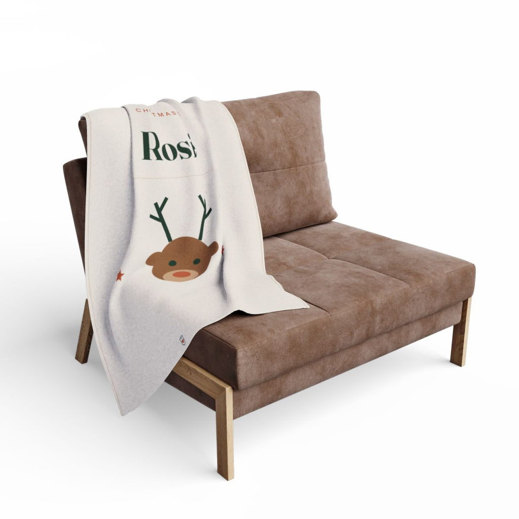 Christmas Eve fleece blanket mock-up draped over a brown armchair, the reindeer face and part of 'Rosie' visible