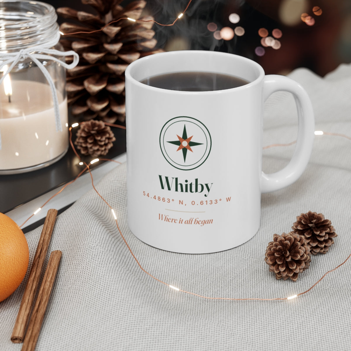 Personalised coordinates mug mock-up filled with coffee on a table with pine cones, a candle and fairy lights