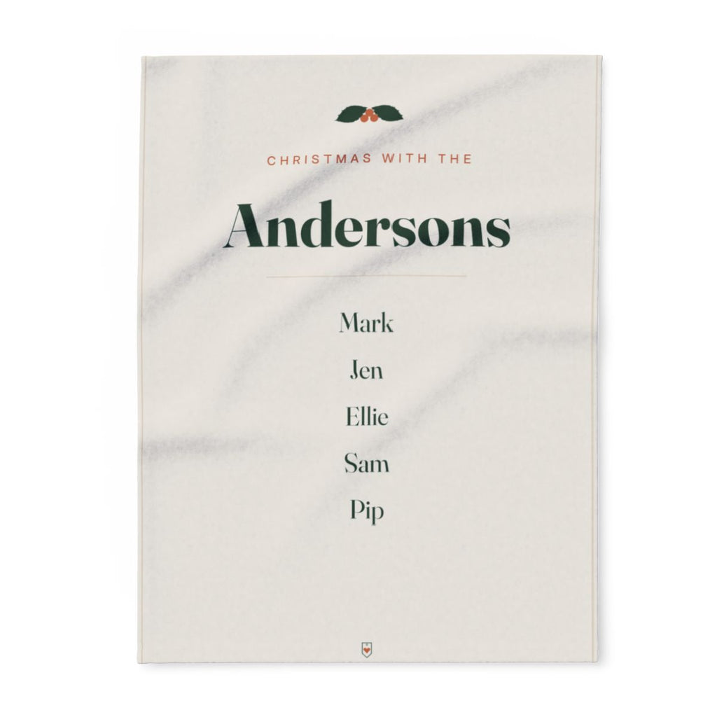 Family Christmas fleece blanket mock-up laid flat with holly, 'Christmas with the Andersons' and five sample names