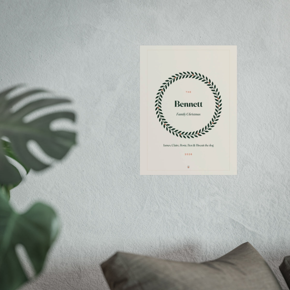 Personalised family Christmas print mock-up at the larger size on a pale wall above a sofa beside a monstera plant