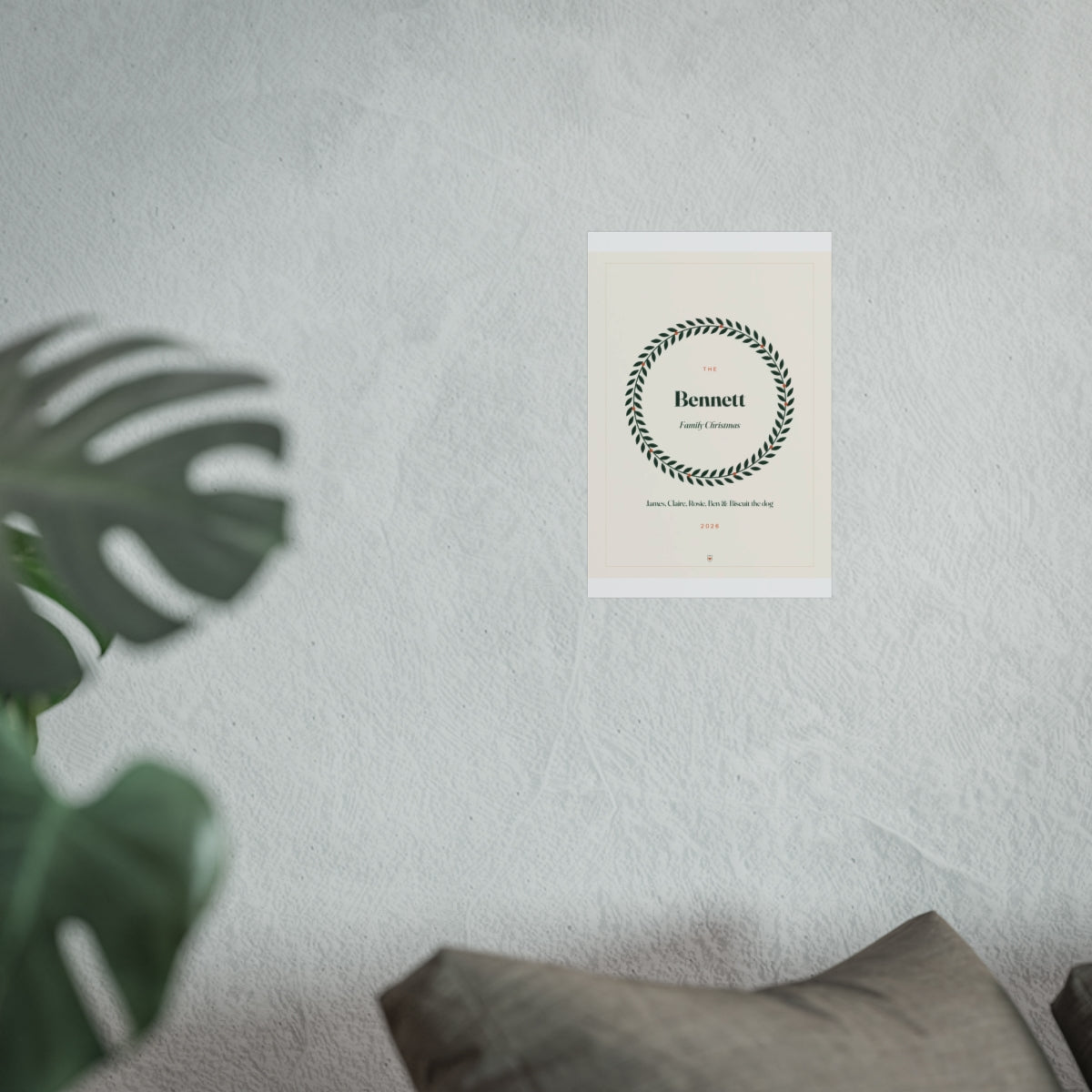 Personalised family Christmas print mock-up at the smaller size on a pale wall above a sofa beside a monstera plant