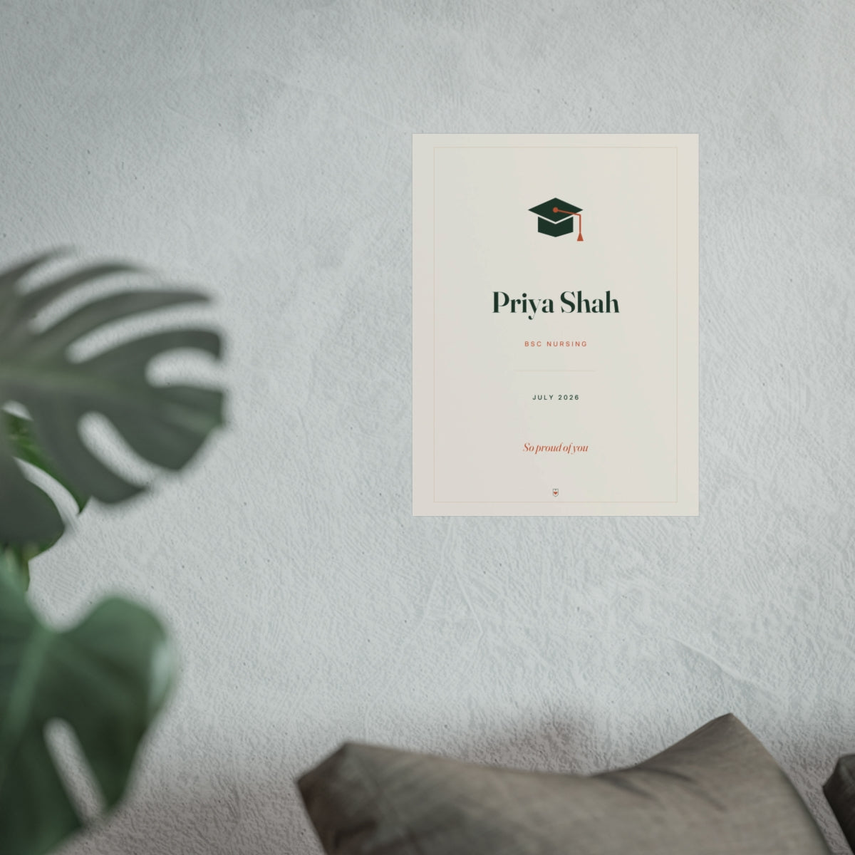 Personalised graduation print mock-up at the larger size on a pale wall above a sofa beside a monstera plant