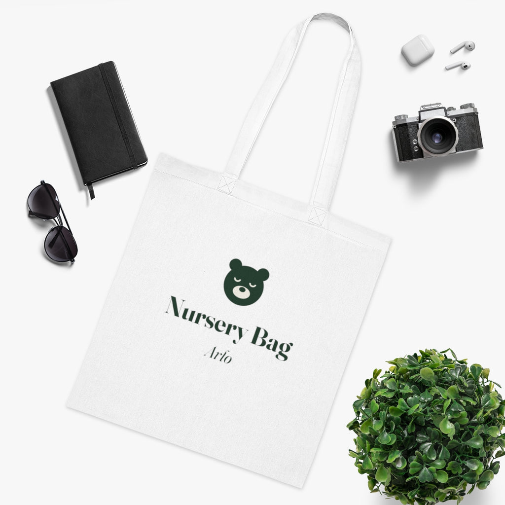Nursery bag tote mock-up from above beside a notebook, sunglasses, earbuds, a camera and a pot plant