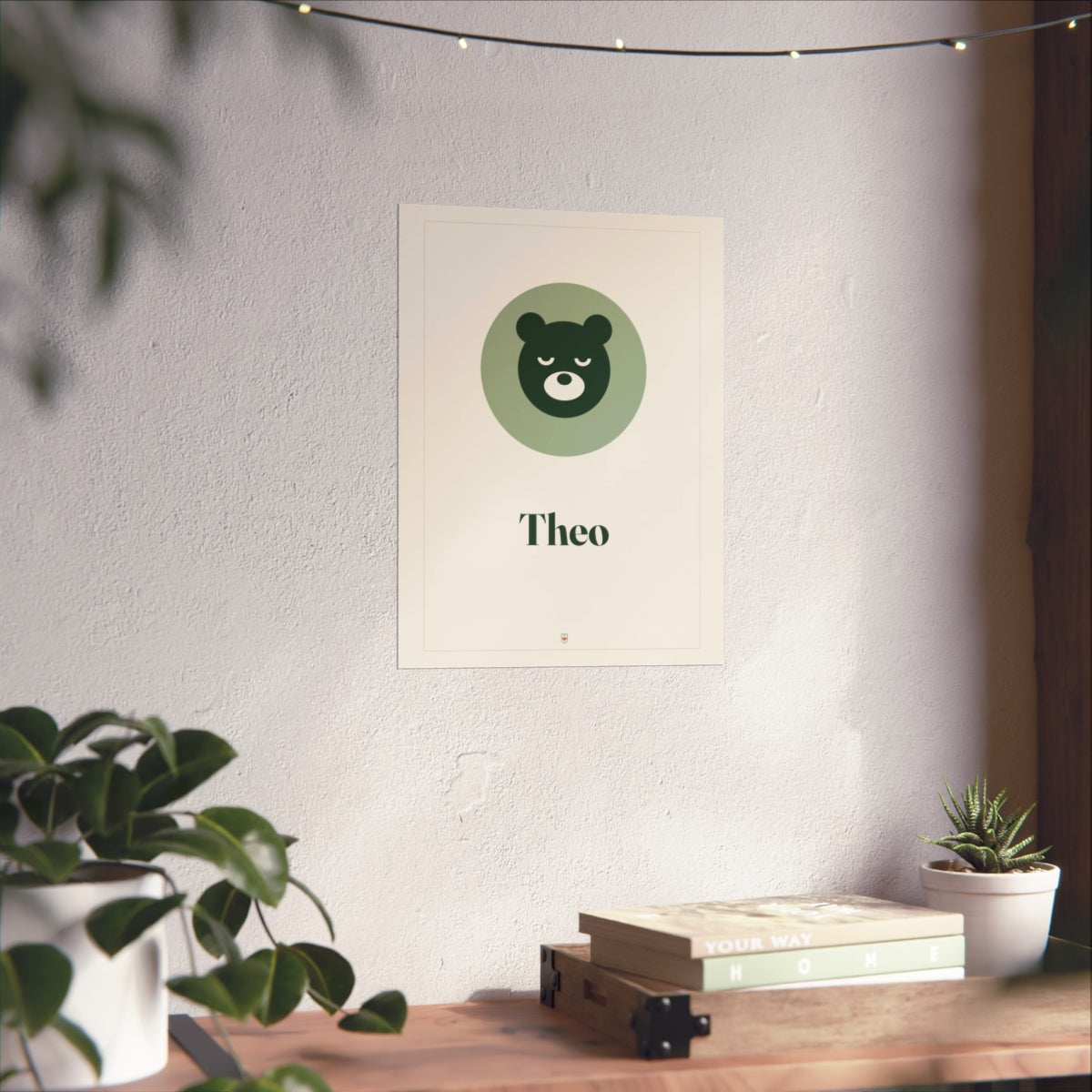 Nursery name print mock-up in the larger size on a sunlit white wall above a wooden shelf with books and plants