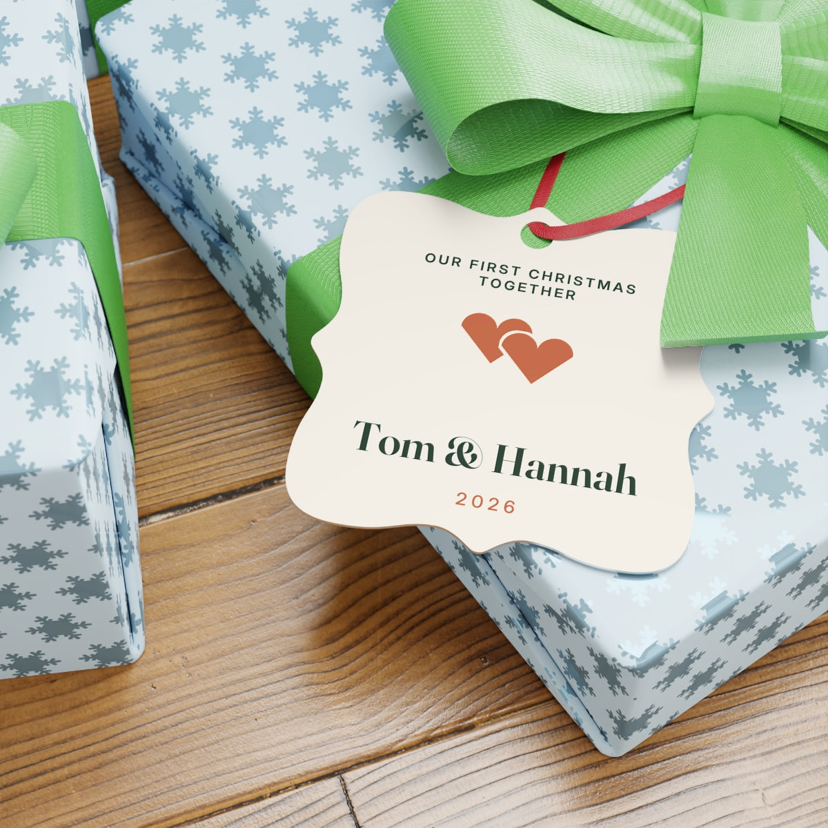 First Christmas together aluminium ornament mock-up resting on snowflake-wrapped gifts with green bows, '2026' in terracotta