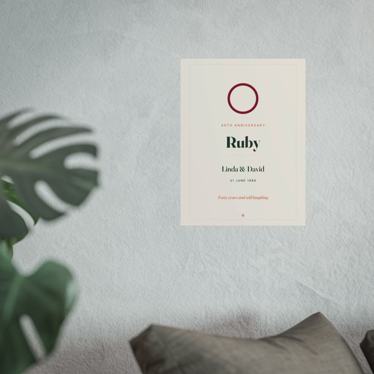 Ruby anniversary print mock-up hung on a pale wall beside a monstera plant and a grey sofa, shown at the larger size