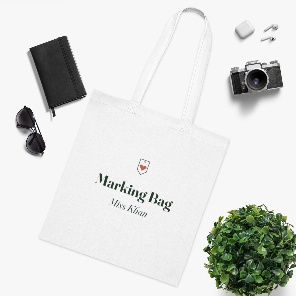 Teacher tote bag mock-up in a flat lay with a notebook, sunglasses, camera, earbuds and a leafy plant