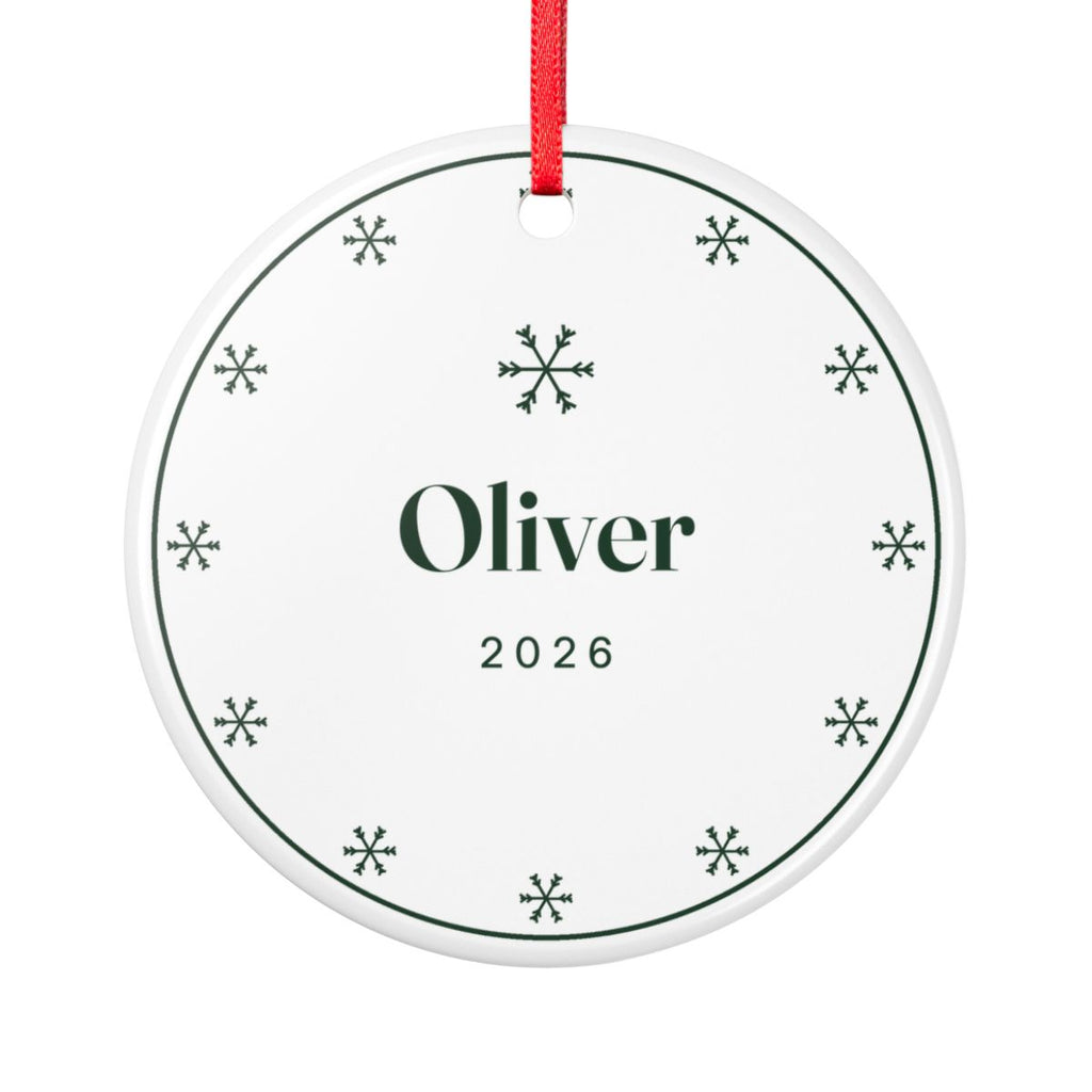 Snowflake ceramic Christmas ornament mock-up, round with a red ribbon, a ring of green snowflakes, 'Oliver' and '2026'